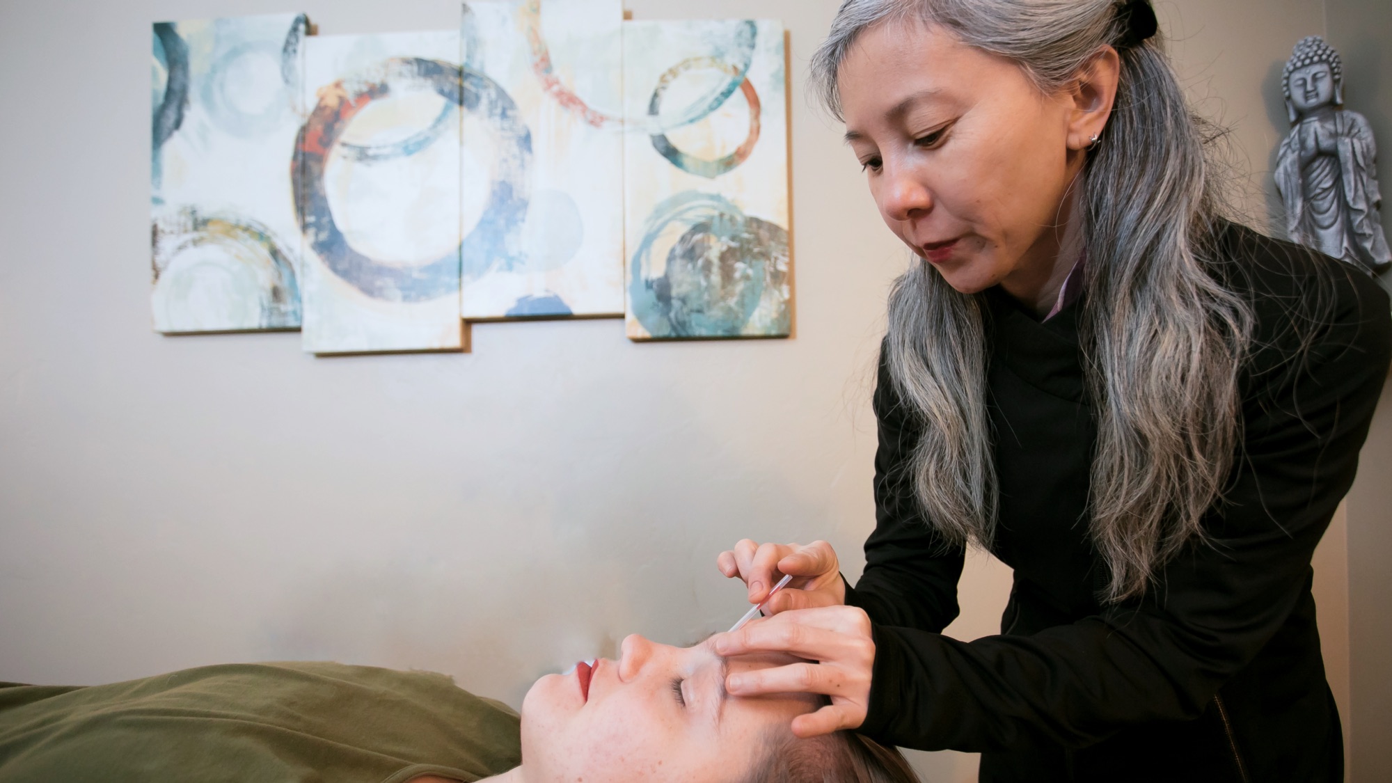 Sang Montage administering acupuncture to a woman.